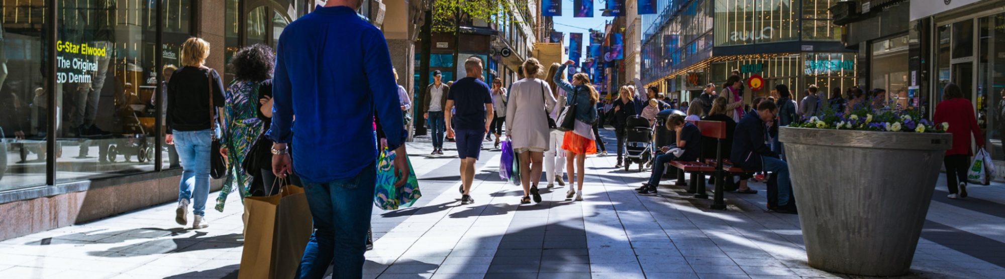Solig shoppinggata med människor