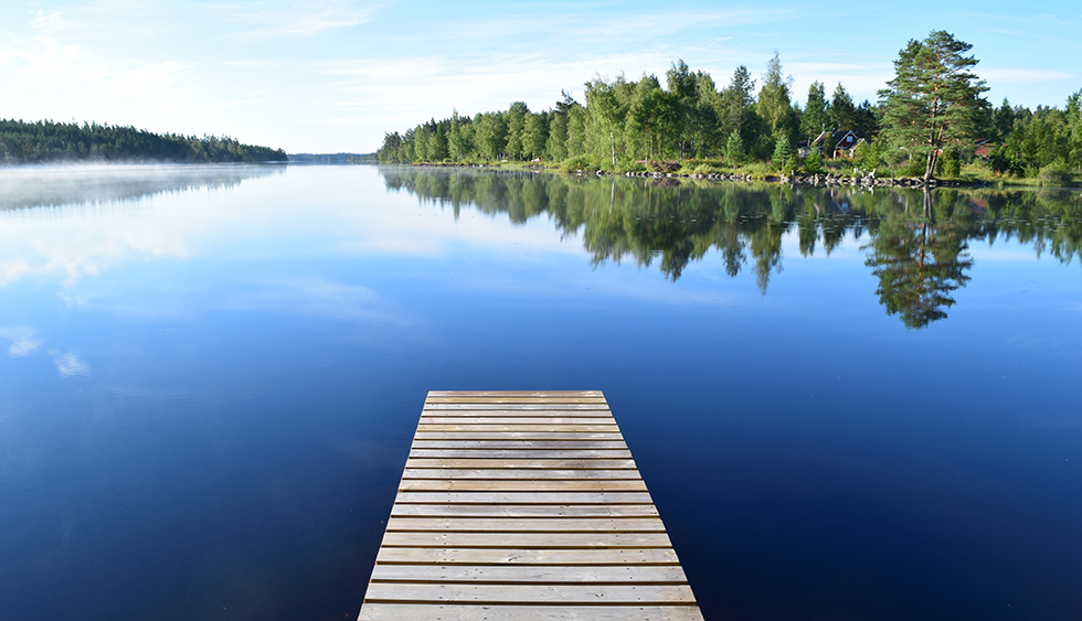en blank sommarsjö med brygga i förgrunden
