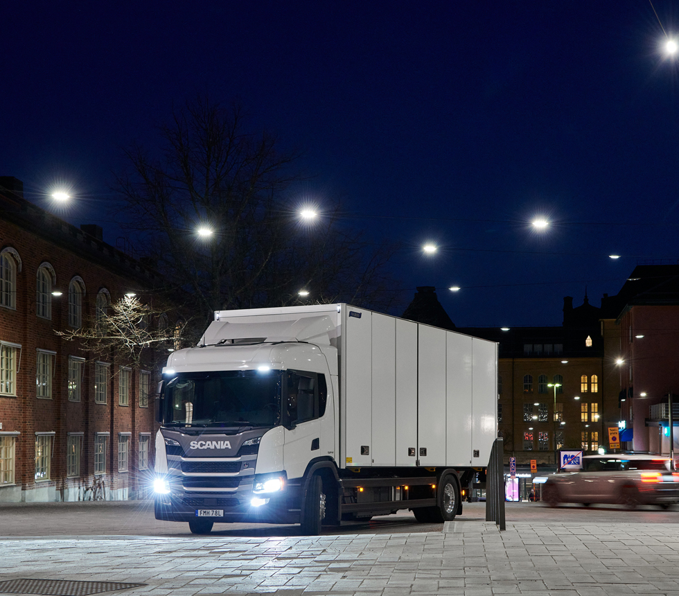 vit lastbil på ett torg under natthimmel