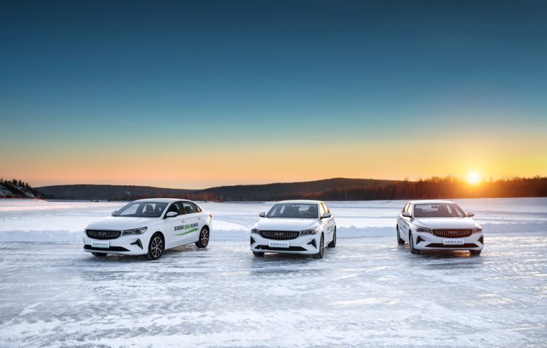 tre vita bilar på isen av en sjö med solnedgång i bakgrunden